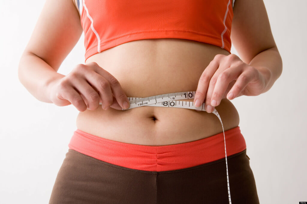 Mid adult woman measuring her waist